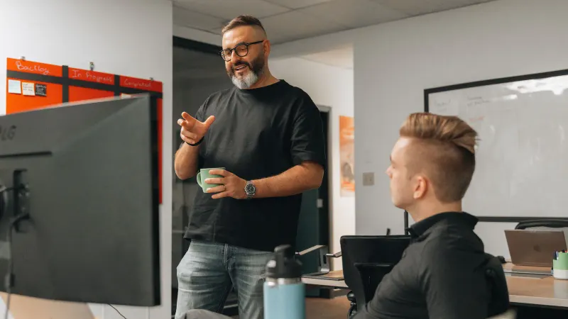 A Setsail strategist with a mug talking a colleague through a plan in the office.
