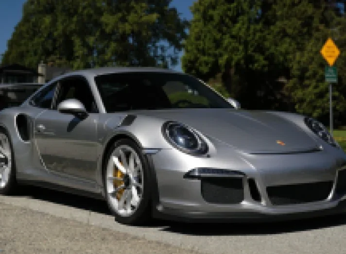 A silver Porsche 911 GT3 parked on a tree-lined street
