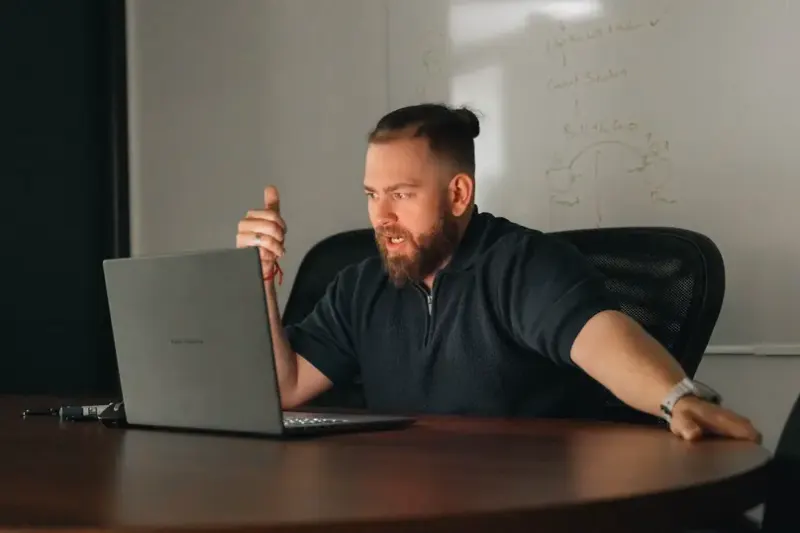 A strategist leaning over a laptop at a meeting table