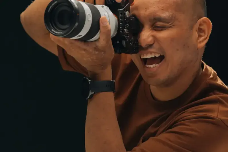 A photographer laughing behind his camera
