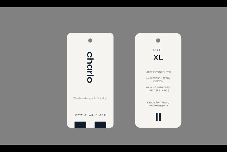 Two Charlo clothing tags on a grey ground