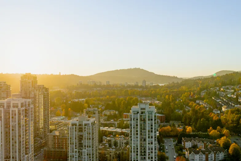 High-rise towers in Coquitlam at sunset, with forested hills behind