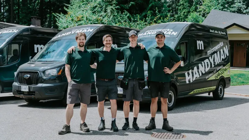 The Microworks Handyman crew standing in front of their branded vans on a North Shore street