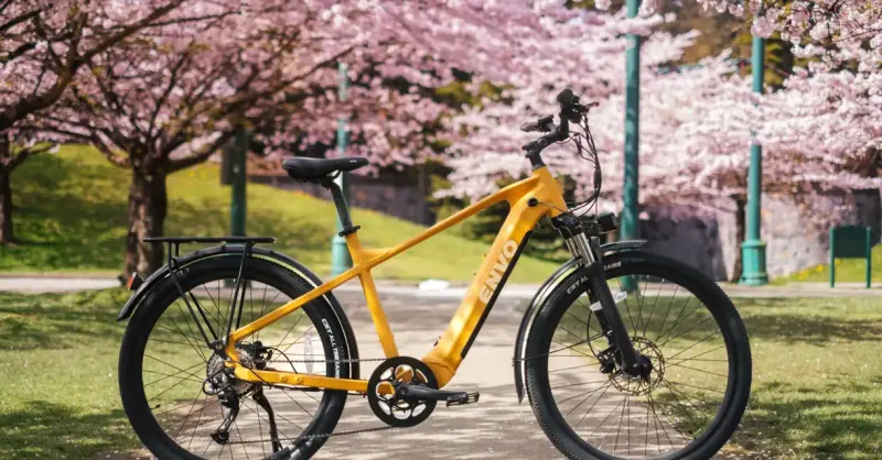 A yellow DŌST e-bike under cherry blossoms