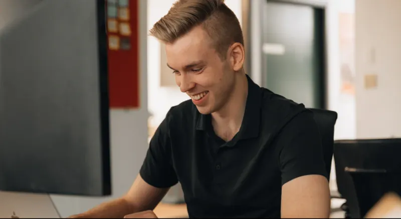 A Setsail team member smiling at his laptop in the studio