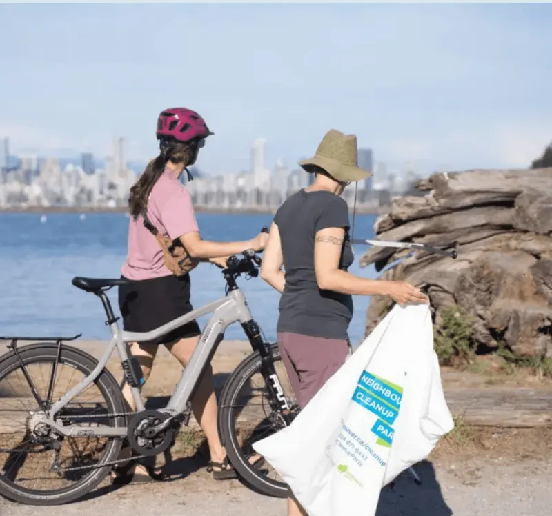 Two volunteers with a bike and a full litter bag on the Vancouver shoreline, from Fairware’s Reeve x Fairware Shoreline Cleanup email