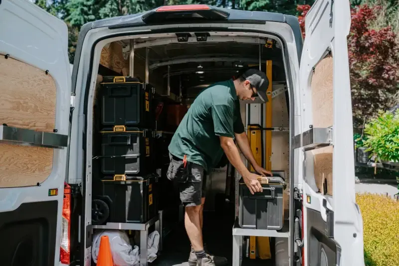 A Microworks technician lifting a tool case out of the racking in his van