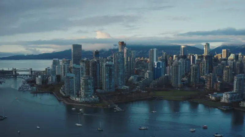 Downtown Vancouver and False Creek at dusk, with mountains behind