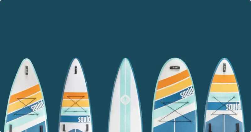 Row of five Squid paddleboard tips with striped graphics on a dark blue ground, wider crop