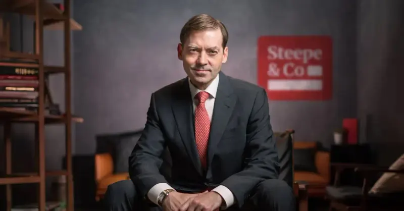 Seated Steepe & Co executive in a dark suit and red tie, with the red Steepe & Co logo on the wall behind