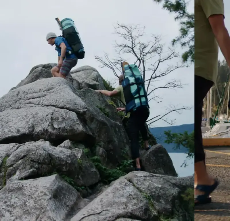 Two hikers carrying Squid paddleboard backpacks while scrambling over coastal rocks