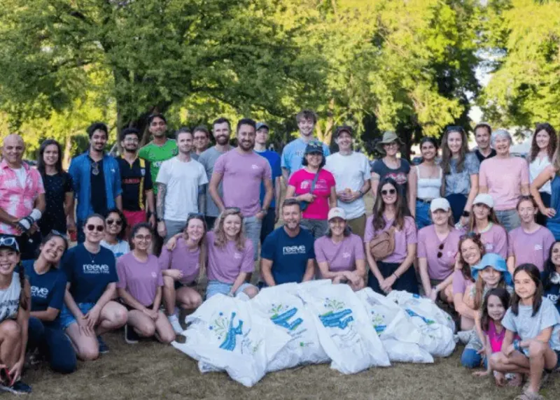 Volunteers in Reeve and Fairware T-shirts beside a pile of full litter bags at the shoreline cleanup in Vancouver