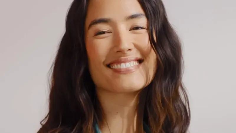 A smiling nurse in dark Healing Hands scrubs with a stethoscope