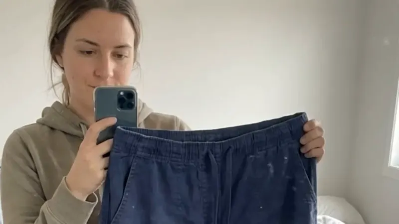 A creator holding up a worn pair of scrub trousers in a mirror selfie, from a UGC-style ad
