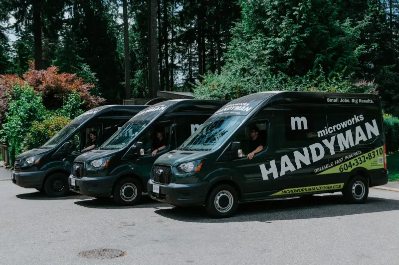 Three branded Microworks vans lined up on a tree-lined street