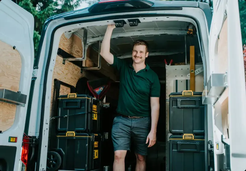 A smiling Microworks technician standing in the back of his fully stocked van