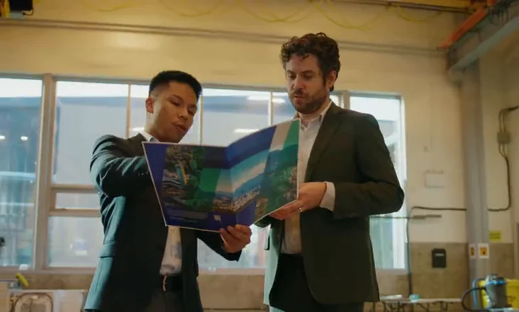 Two businessmen reviewing an Invest Vancouver brochure on a manufacturing floor
