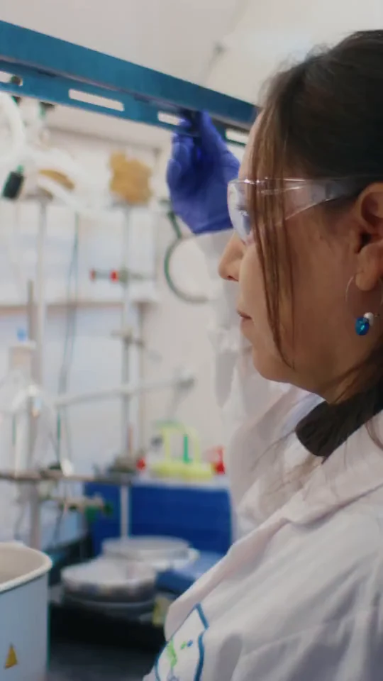A scientist in safety glasses and a lab coat at work in a research lab