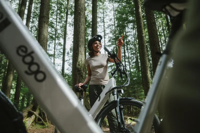 A rider beside her EBGO e-bike in the forest, the ebgo frame in the foreground