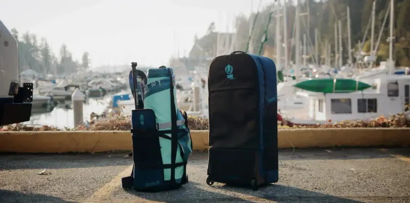 Shoreline Skeleton backpack and wheeled Shoreline travel bag standing on a marina waterfront
