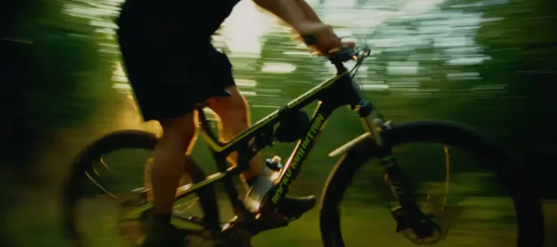 A rider on a mountain bike, blurred with speed against green woods