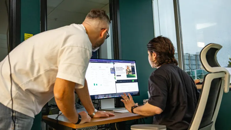 A Setsail strategist leaning in to coach a colleague at his monitor.
