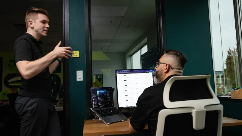 A Setsail strategist standing to explain a plan to a colleague at his desk.