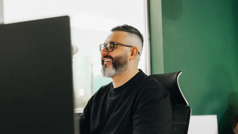 A Setsail strategist in glasses smiling at his desk behind a monitor.
