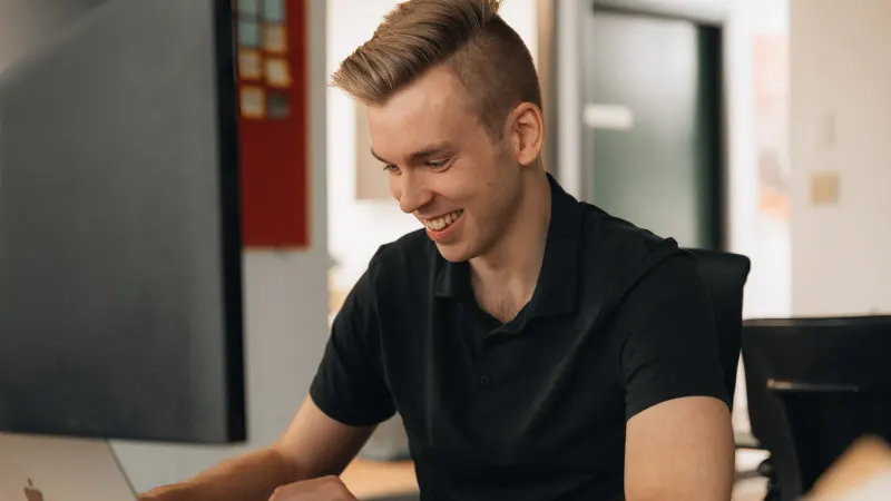 A Setsail designer smiling as he works through a site at his monitor.