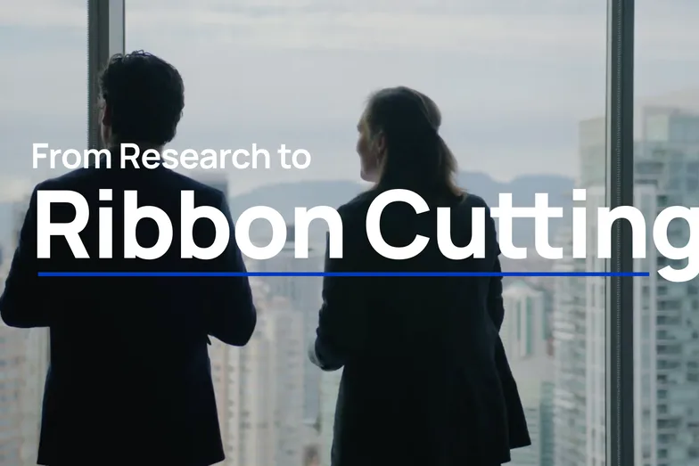 A man in a suit at an office window over the city, titled “From Research to Ribbon Cutting”