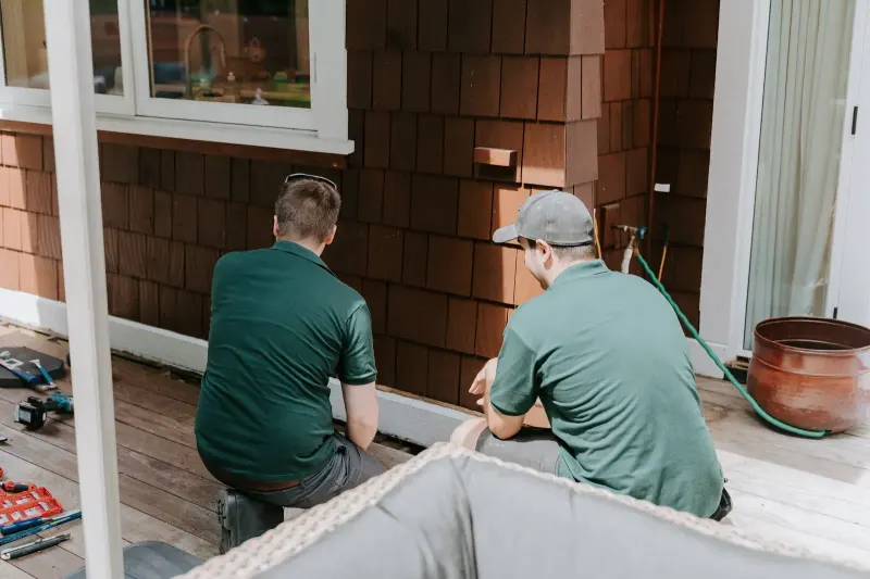 Two Microworks technicians working side by side at the base of a house
