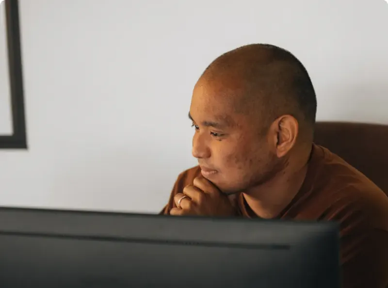 A man at his monitor, chin resting on his hand, reading the screen