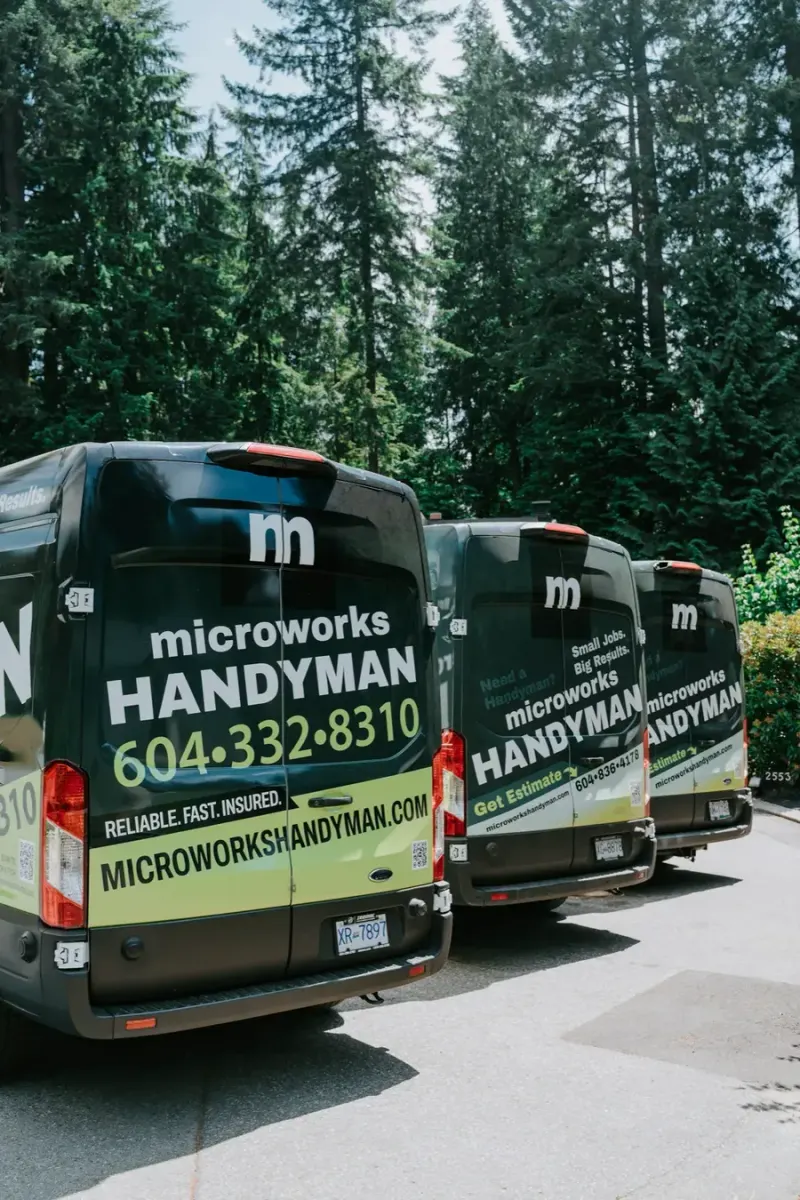 Three Microworks vans parked in a row, seen from behind with the phone number and website on the doors