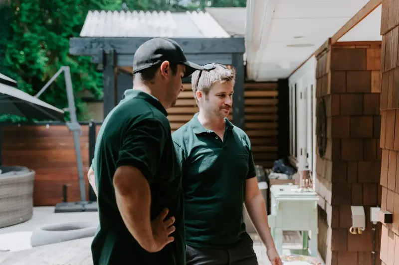 Two Microworks technicians talking through a job on a backyard deck