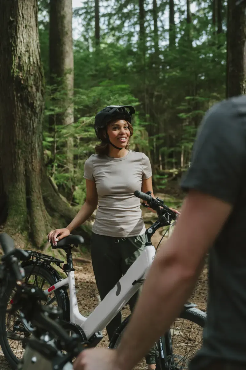A smiling rider standing with her EBGO e-bike among the trees