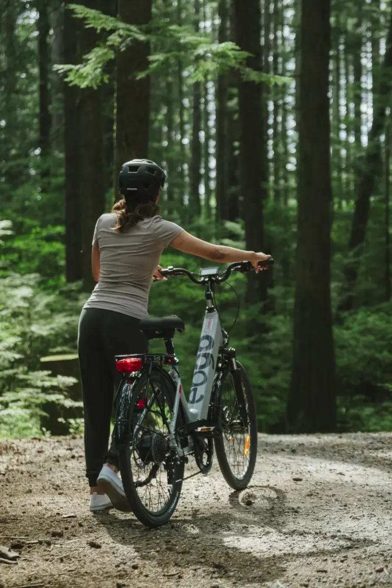 A rider walking her EBGO e-bike down a gravel trail