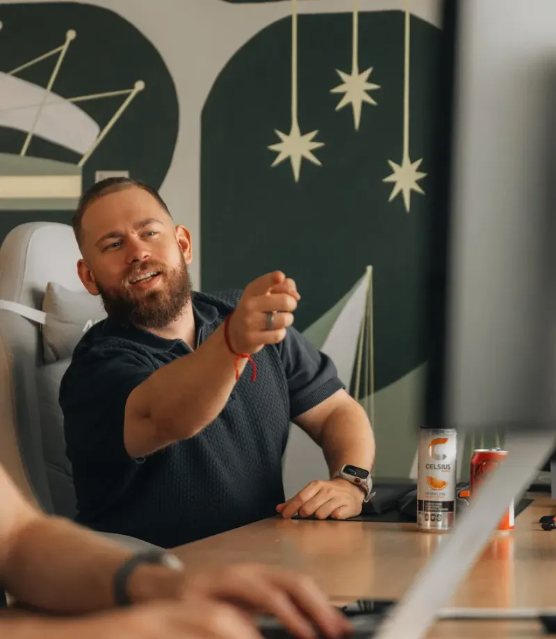 A team member at his desk in the studio, pointing as he explains