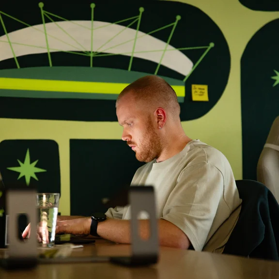 A Setsail SEO & GEO specialist at his laptop under the studio mural