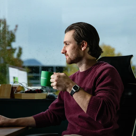 A Setsail Account lead with a coffee at his desk by the window