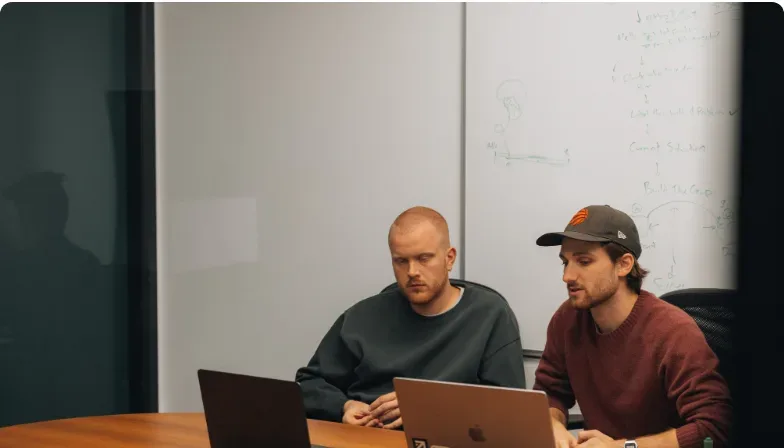 Two Setsail colleagues in a meeting at a table with their laptops