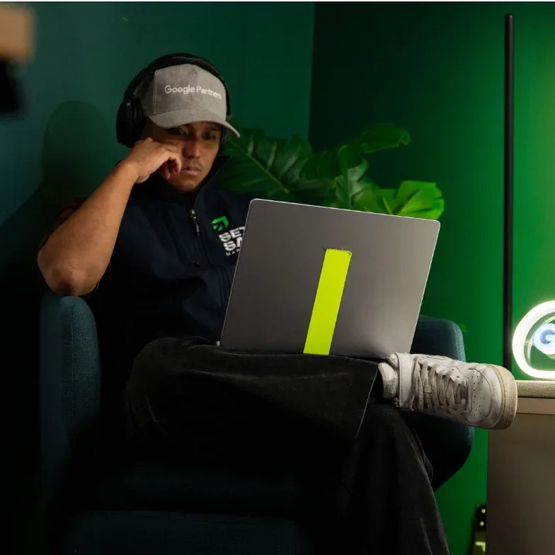 A Setsail paid ads specialist working on a laptop by the green wall