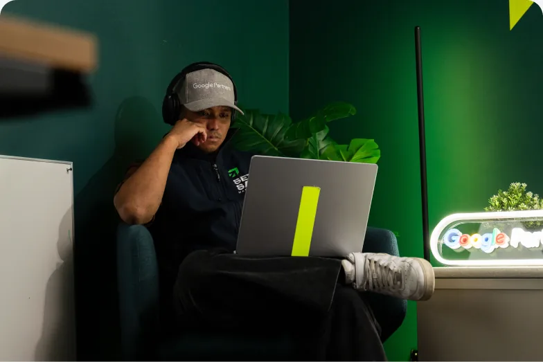 A Setsail Marketing team member in headphones working on his laptop beside the studio’s Google Partners sign