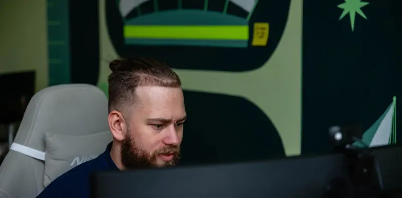 A bearded Setsail team member focused on his monitor, in front of a painted mural