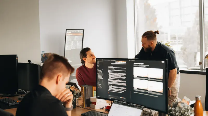 Three Setsail team members at work in the office, one at a monitor full of code