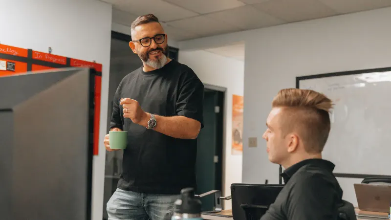 A Setsail strategist with a mug talking a colleague through the work at his desk.