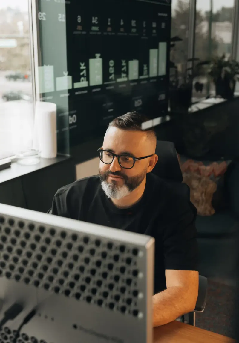A Setsail team member at his desk in front of a wall of client results
