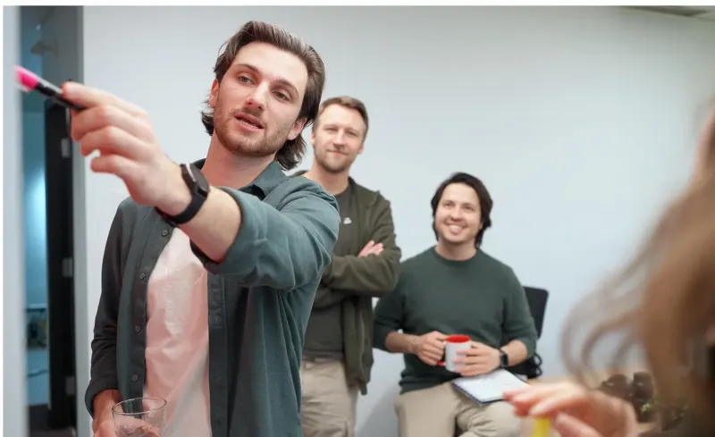Setsail team member pointing at a whiteboard with a marker during a brand workshop while two colleagues look on