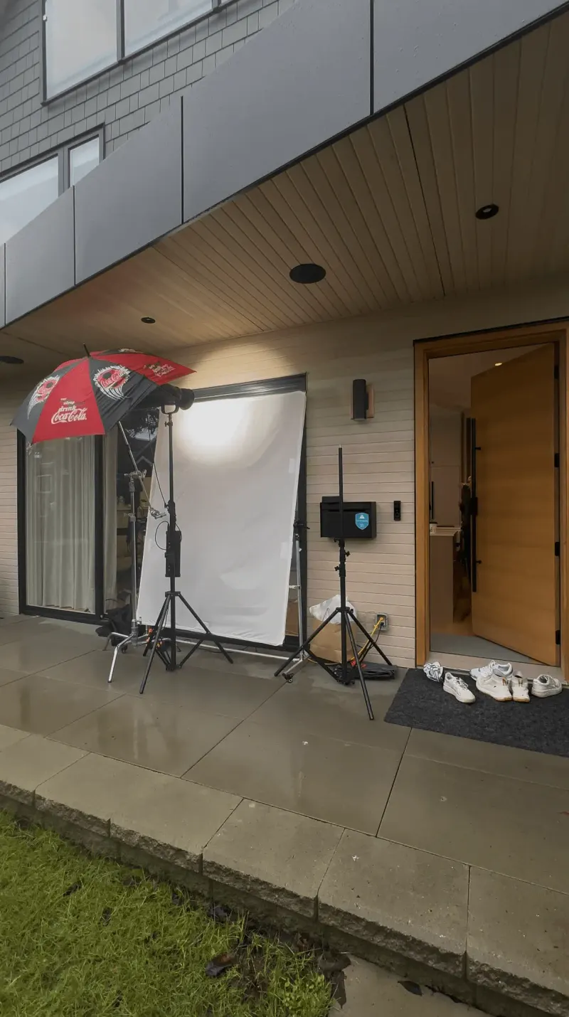 Behind the scenes at the BC Hydro shoot: lighting stands, a diffusion screen and a reflector umbrella outside a house