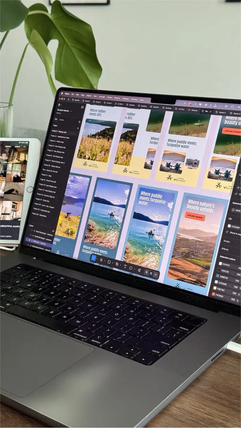 Laptop showing a Figma file of Tourism Vernon vertical display ads with lake, cyclist and paddler photos