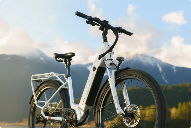 A white DŌST e-bike in front of snow-capped mountains